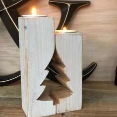 a wooden candle holder with a christmas tree cut out of it and two candles in the middle