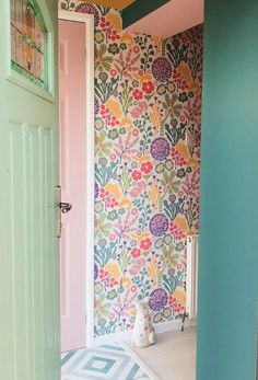 an open door leading to a brightly colored room with floral wallpaper on the walls