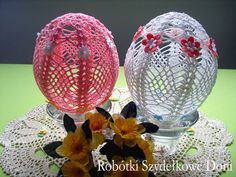 two glass vases sitting on top of a doily with flowers in front of them