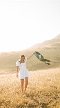 a woman in a white dress is holding a green and yellow scarf over her head