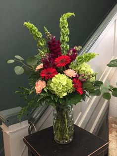 a vase filled with lots of flowers on top of a table next to a stair case