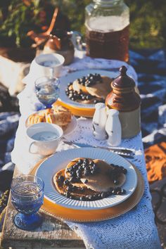 a table topped with plates of food next to bottles of water and jars filled with honey