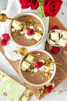 two bowls filled with chocolate pudding and topped with raspberries next to a red rose