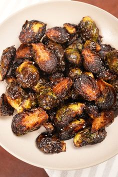 a white plate topped with roasted brussel sprouts on top of a wooden table