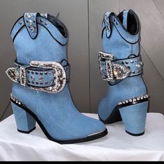 a pair of blue cowboy boots with silver buckles and crystals on the side, sitting on a white cloth