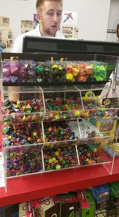 a man standing in front of a display case filled with lots of different colored beads