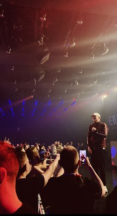 a man standing on top of a stage in front of a crowd at a concert