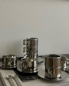 there are silver cups and saucers on the trays that have been placed on top of each other