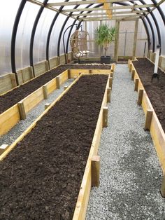 several rows of wooden planters filled with dirt in a small garden area that is enclosed by a metal frame