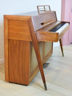 an old wooden piano sitting on top of a hard wood floor next to a pink door