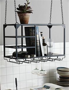 a hanging shelf filled with books and wine bottles next to a wall mounted potted plant