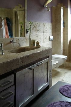 a bathroom with two sinks and purple rugs