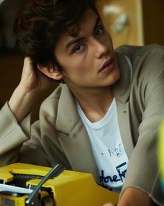 a young man sitting at a table next to a yellow box with scissors in it