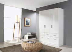 a living room filled with furniture next to a tall white wall mounted cabinet and floor lamp