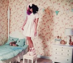 a woman standing on top of a bed next to a small child's bed