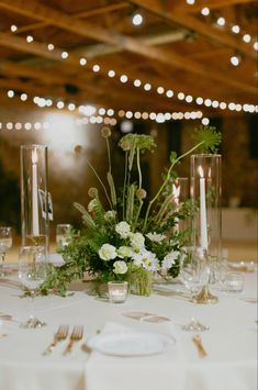 the table is set with candles, flowers and greenery for an elegant wedding reception