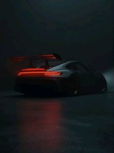 a black sports car in the dark with red lights on it's taillights