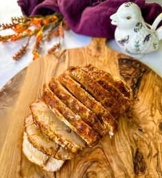 slices of meat sitting on top of a wooden cutting board next to a teapot