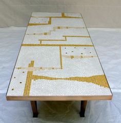 a table that has some kind of mosaic design on top of it, sitting on a white sheet