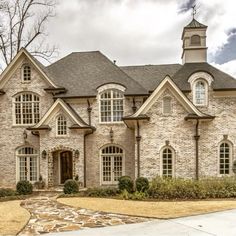 a large brick house with arched windows and a stone walkway leading to the front door