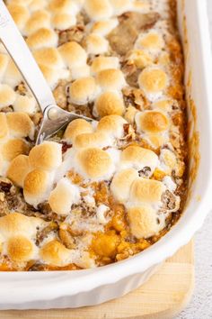 a casserole dish with marshmallows in it and a spatula