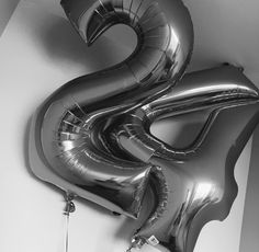 black and white photograph of balloons shaped like the number twenty five in front of a wall