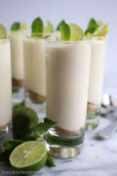 three glasses filled with pudding and garnished with limes on a marble table