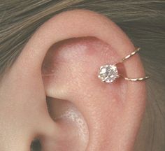 a close up of a person's ear with a single diamond in the middle