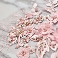 pink flowers and pearls are on the fabric