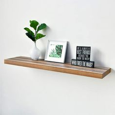 there is a plant and two framed pictures on the shelf next to eachother