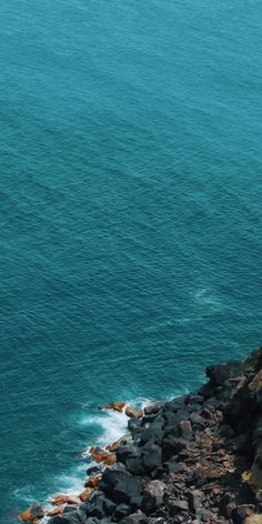 two people standing on top of a cliff near the ocean