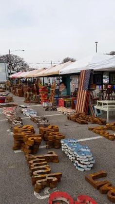 an outdoor flea market with lots of wooden items on the ground and tents in the background