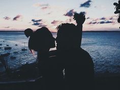 a man and woman standing next to each other near the ocean