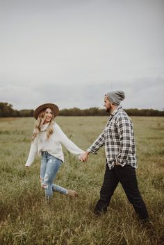 a man and woman holding hands in a field