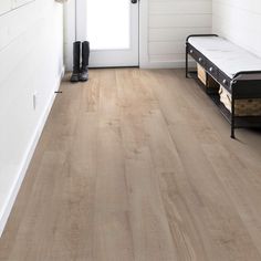 a white room with wood flooring and a bench in front of the door that is open