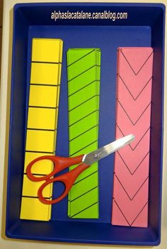 a pair of scissors sitting on top of some colored strips