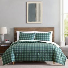 a green and white plaid comforter set on a bed in a room with two lamps