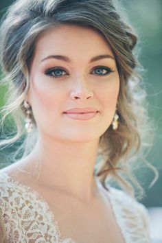 a woman with long hair and blue eyes wearing a white dress is looking at the camera