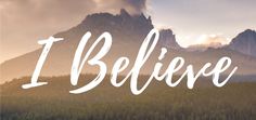 the words i believe are in front of a mountain range with trees and clouds behind it