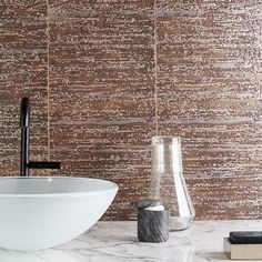 a white bowl sitting on top of a marble counter next to a black faucet