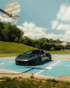 a black sports car is parked in the parking lot next to a basketball hoop on a sunny day