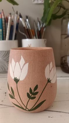 a pink vase with white flowers painted on it