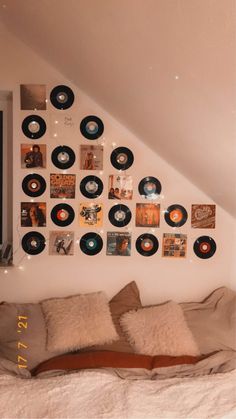 there is a bed with many records on the wall above it and pillows below them