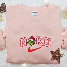 The Grinch Head x Nike Embroidered Shirt is the perfect blend of holiday cheer and street style. Made with high-quality cotton, it features a vibrant embroidered Grinch head and Nike logo, adding a festive touch to your wardrobe. The shirt’s comfortable fit and durable construction ensure long-lasting wear. Whether you’re hitting the gym or attending a holiday party, this shirt will keep you looking cool and festive. Give the gift of style this Christmas with our Grinch Head x Nike E Gingerbread Embroidery, Nike Inspired, Maroon Hoodie, Christmas Gif, Family Christmas Gifts, Hoodie Material, Custom Nikes, Embroidered Sweatshirt, Embroidered Clothes