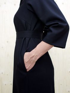 a woman in a black dress with her hands on her hip and the back of her body