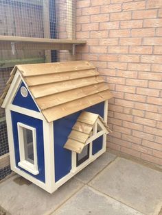 a blue and white dog house sitting on the side of a brick building with a brown roof