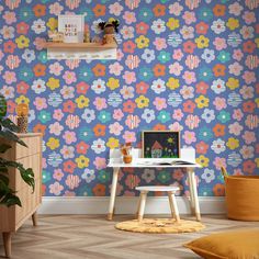 a desk with a laptop on it in front of a flower wallpaper