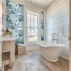 a white bath tub sitting inside of a bathroom next to a wooden counter top under a window