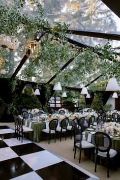 an outdoor dining area with black and white checkered flooring, chandeliers and tables