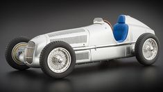 an old fashioned silver race car with blue seats